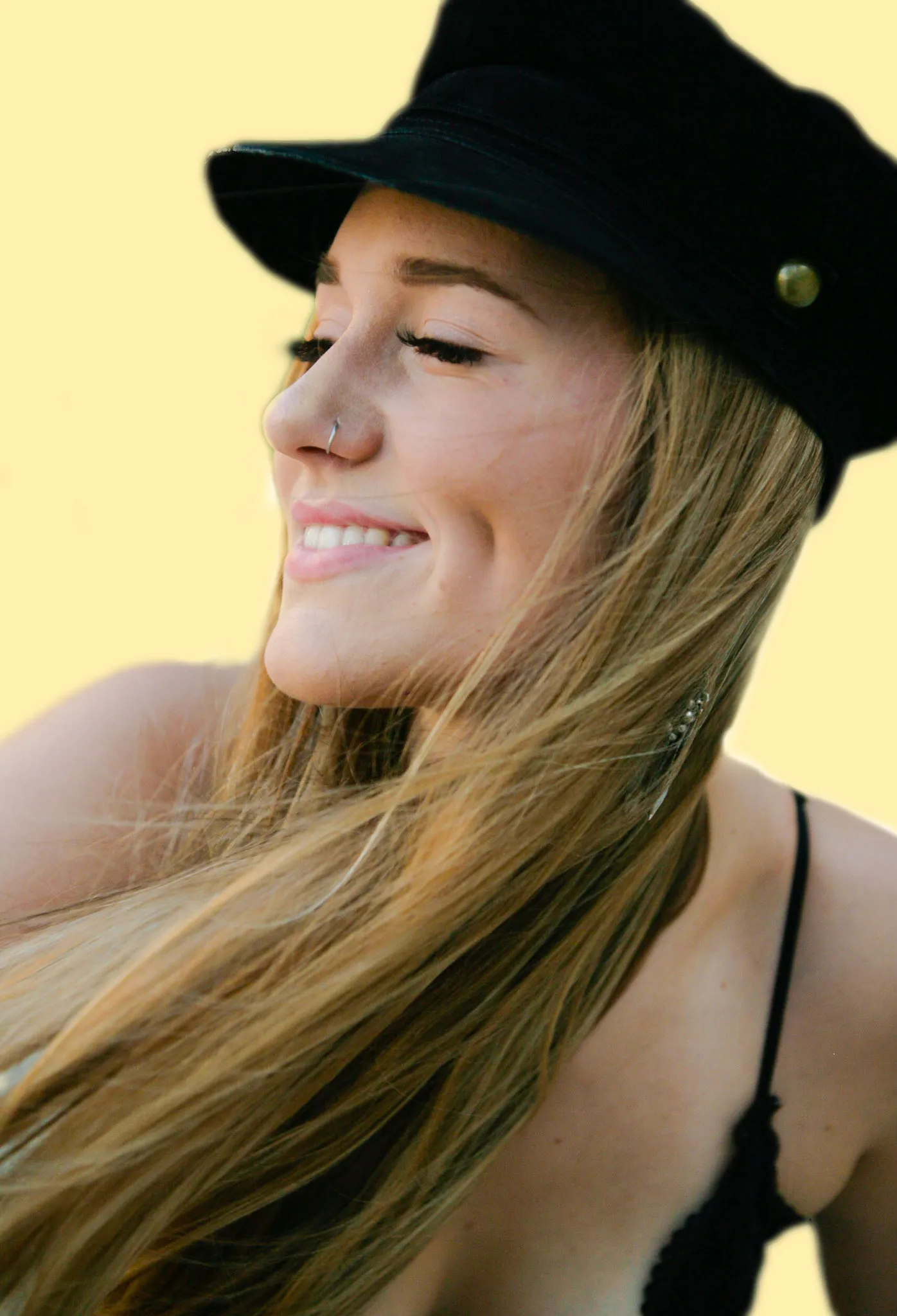 Carrington Smurl, smiling, in a black cap against a yellow background.